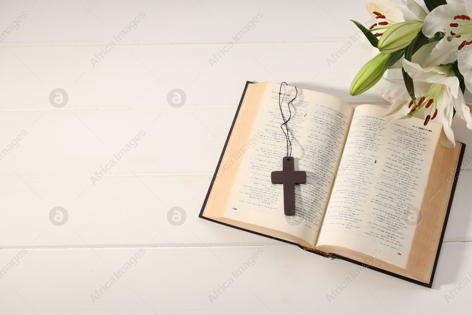 Photo of Cross, Bible and beautiful lily flowers on white wooden table, flat lay with space for text. Religion of Christianity