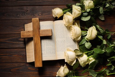 Bible, cross and roses on wooden table, top view. Religion of Christianity