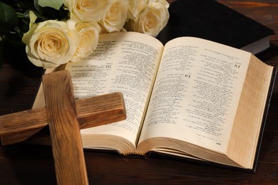 Photo of Bibles, cross and roses on wooden table, closeup. Religion of Christianity