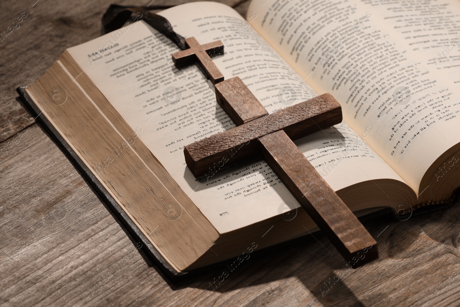 Photo of Bible and crosses on wooden table, closeup. Religion of Christianity