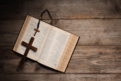 Photo of Bible and crosses on wooden table, top view with space for text. Religion of Christianity