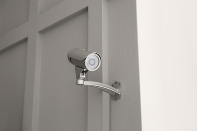 Photo of Modern CCTV camera on light wall indoors