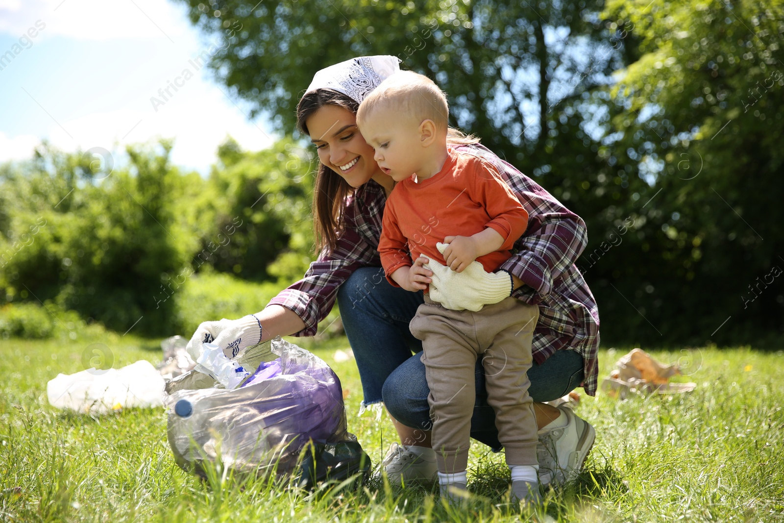 Photo of Mother and her son with plastic bag collecting garbage in park