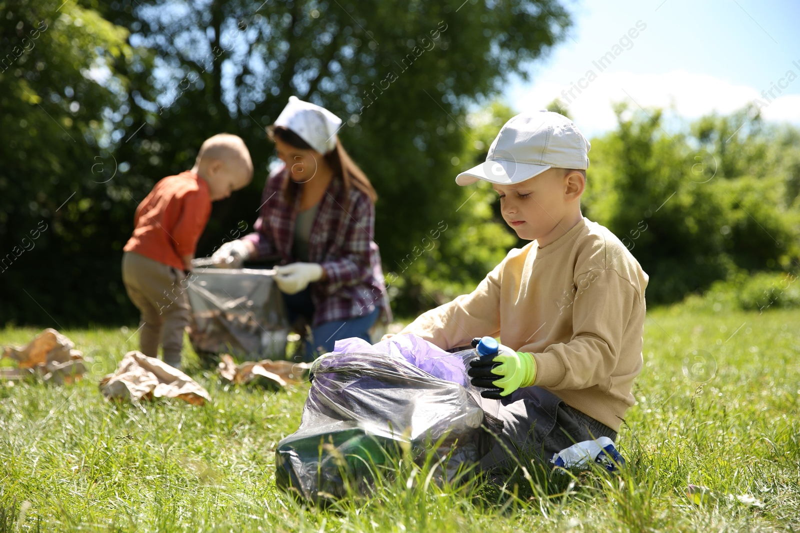 Photo of Mother and her children with plastic bags collecting garbage in park