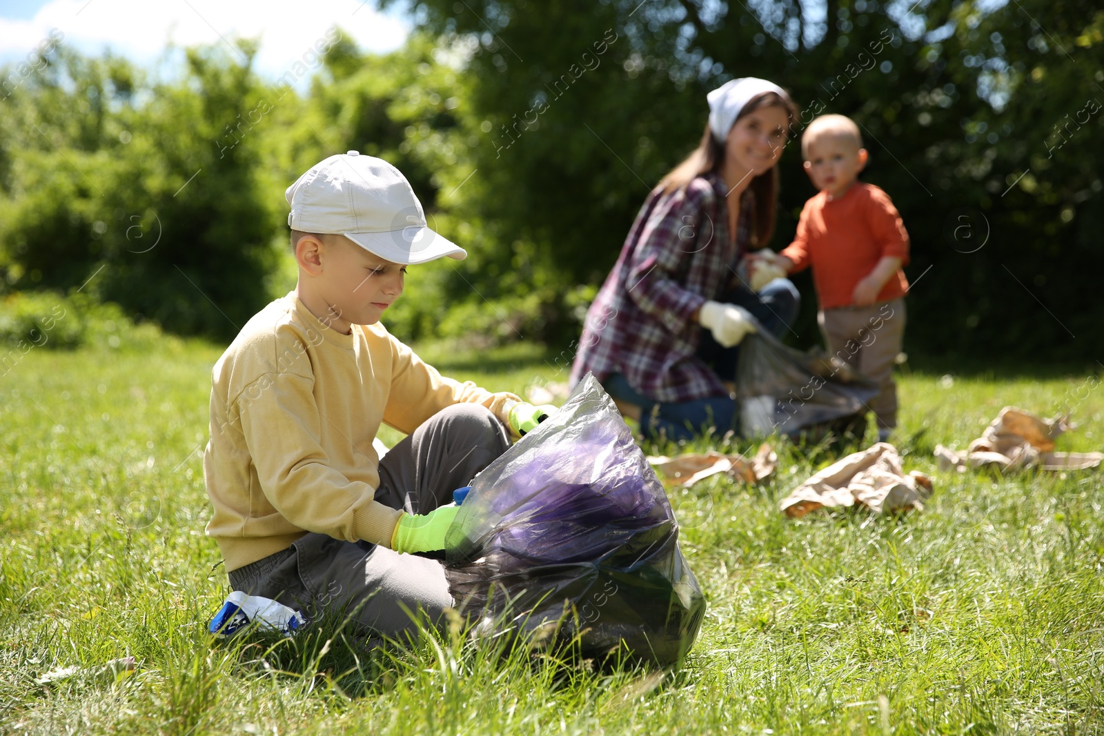 Photo of Mother and her children with plastic bags collecting garbage in park