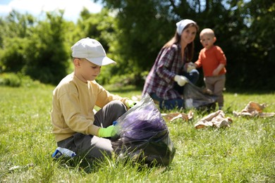 Mother and her children with plastic bags collecting garbage in park