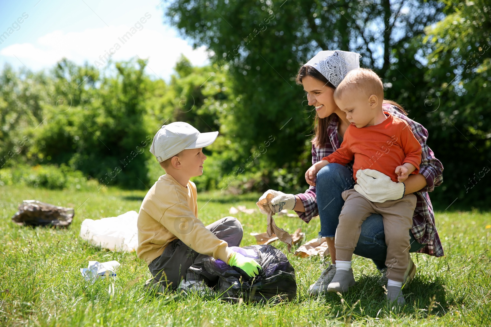 Photo of Mother and her children with plastic bags collecting garbage in park