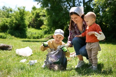 Mother and her children with plastic bags collecting garbage in park