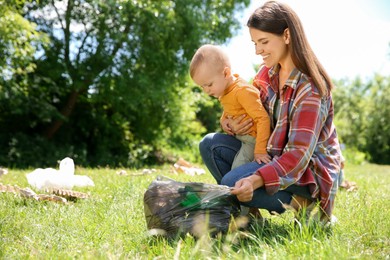 Photo of Mother and her son with plastic bag collecting garbage in park