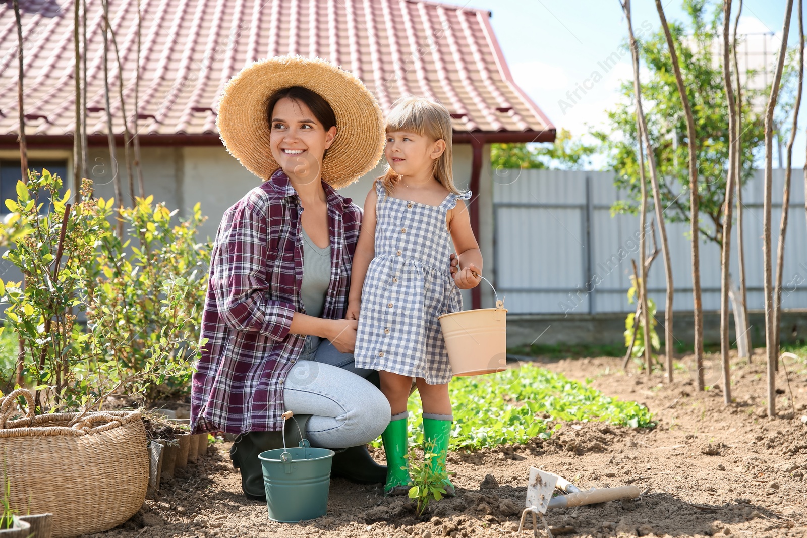 Photo of Mother and her cute daughter planting tree together in garden
