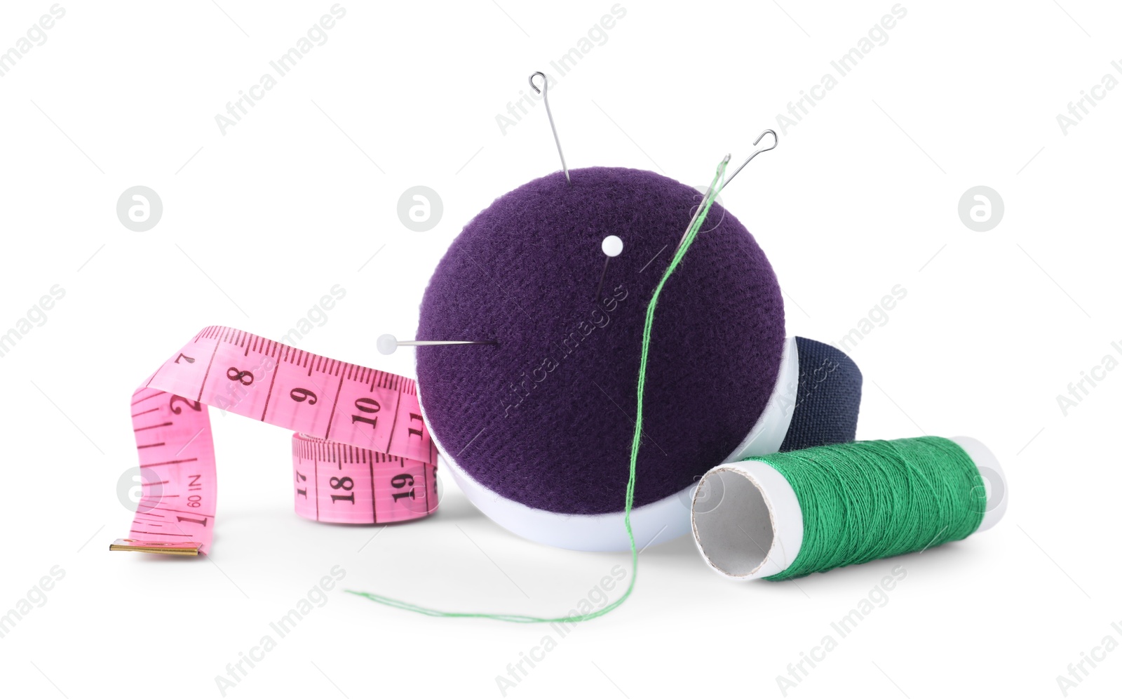 Photo of Pincushion, sewing needles, pins, spool of thread and measuring tape isolated on white