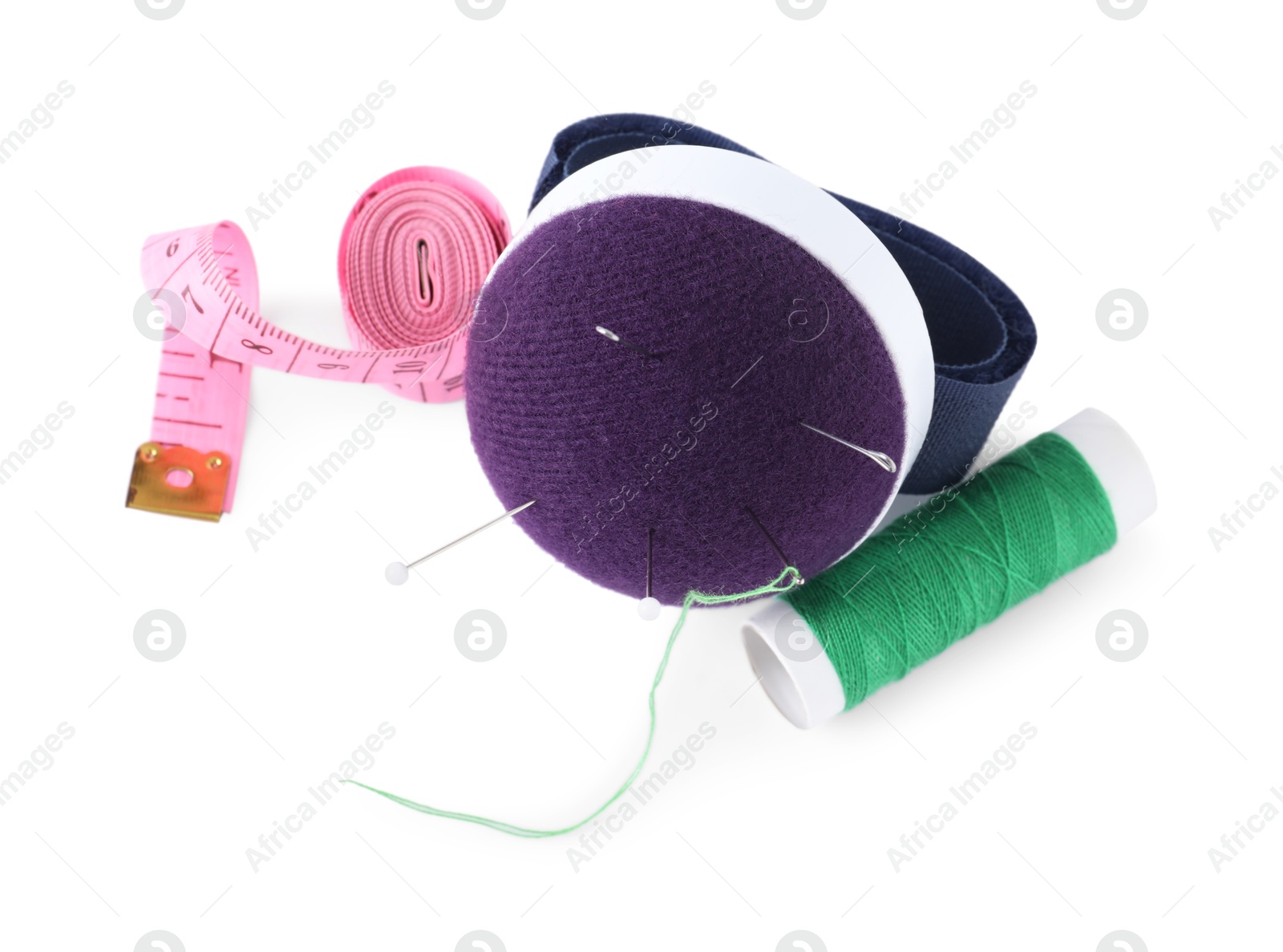 Photo of Pincushion, sewing needles, pins, spool of thread and measuring tape isolated on white, top view