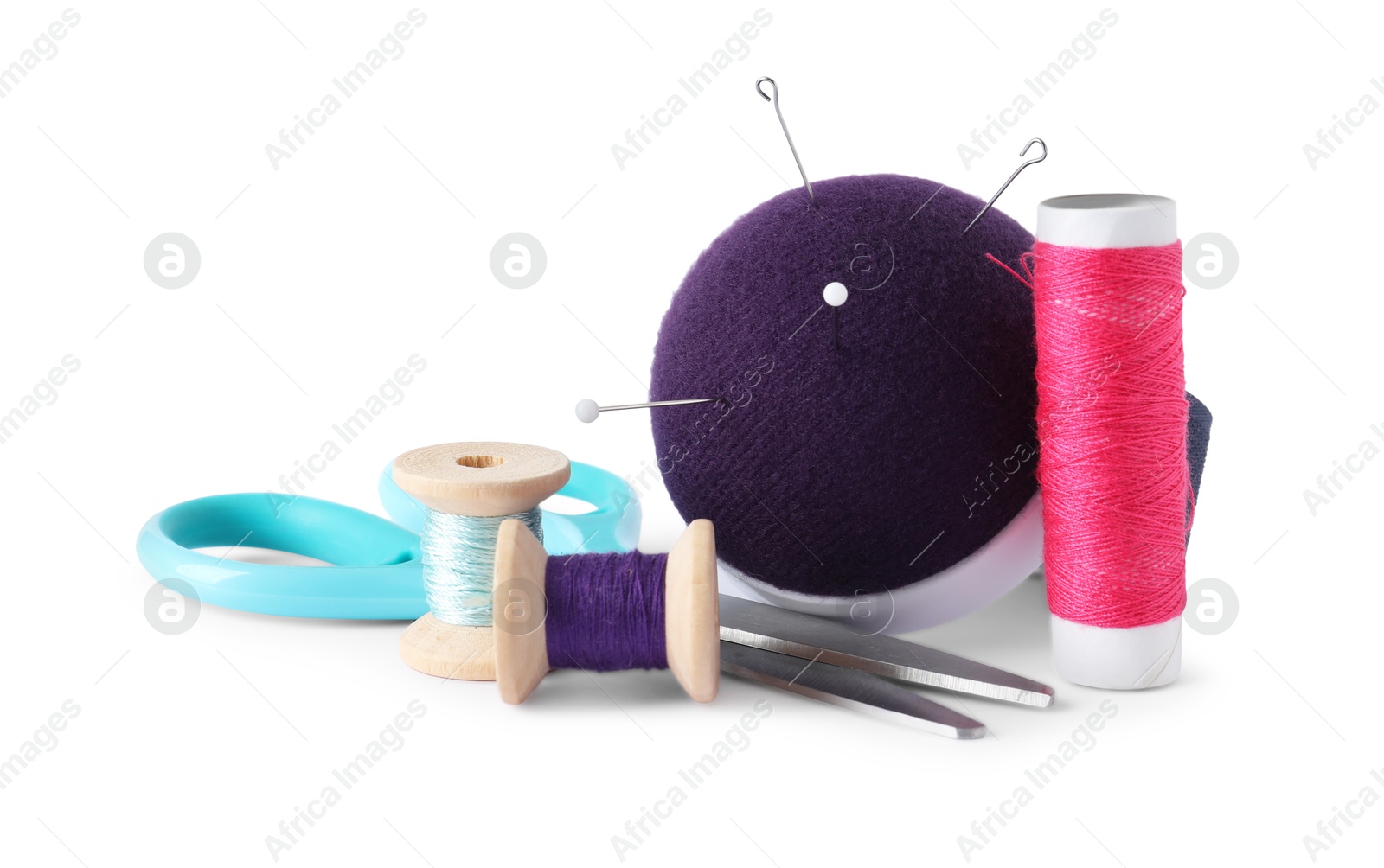 Photo of Pincushion, sewing needles, pins, spools of threads and scissors isolated on white