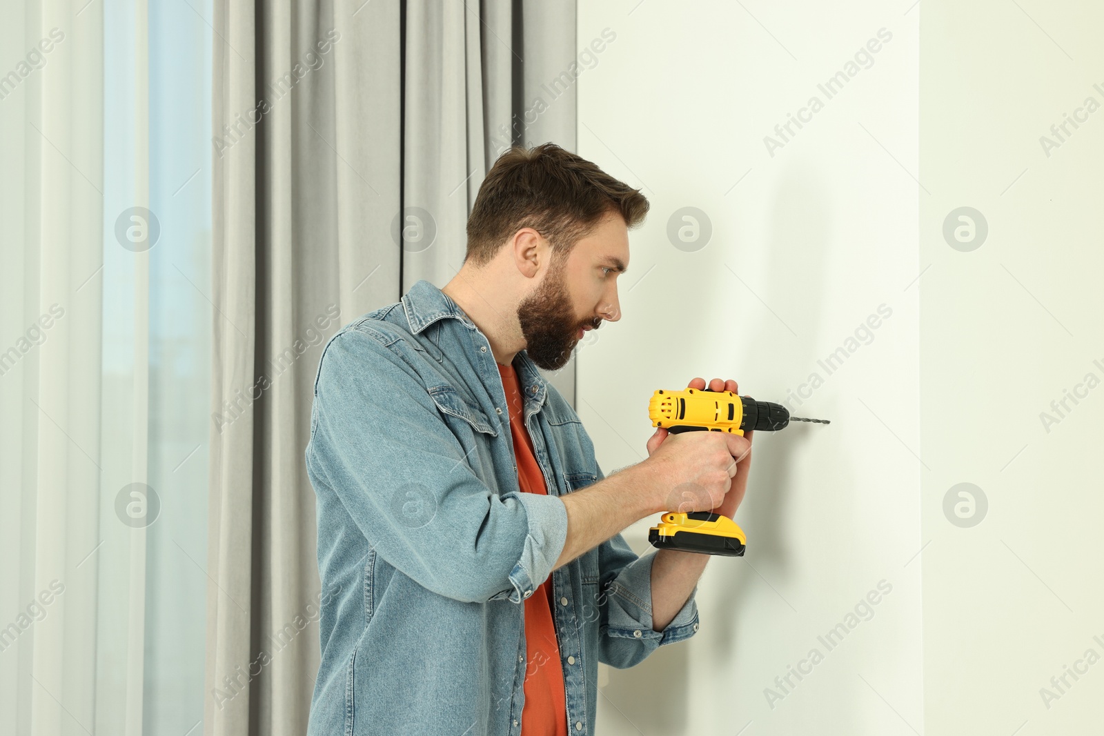 Photo of Man working with drill and wall at home