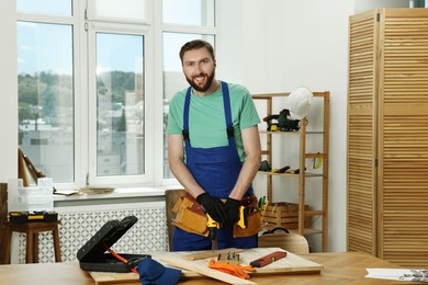 Portrait of smiling craftsman with drill at table in workshop