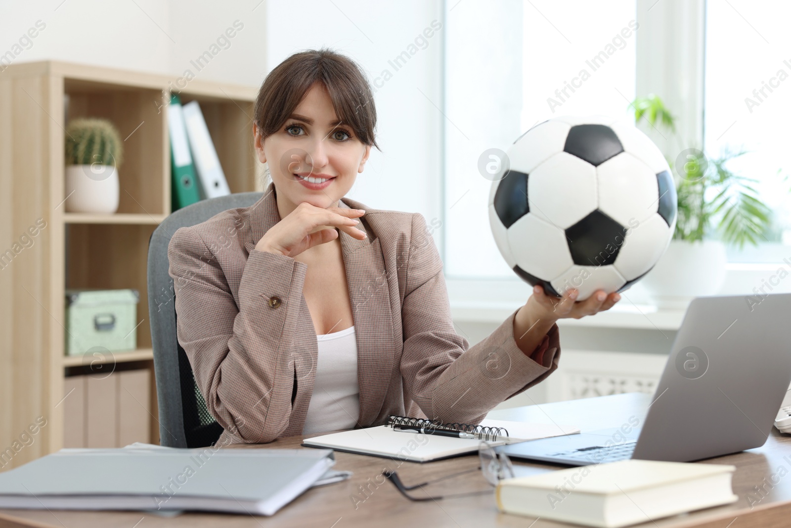 Photo of Smiling employee with soccer ball at table in office