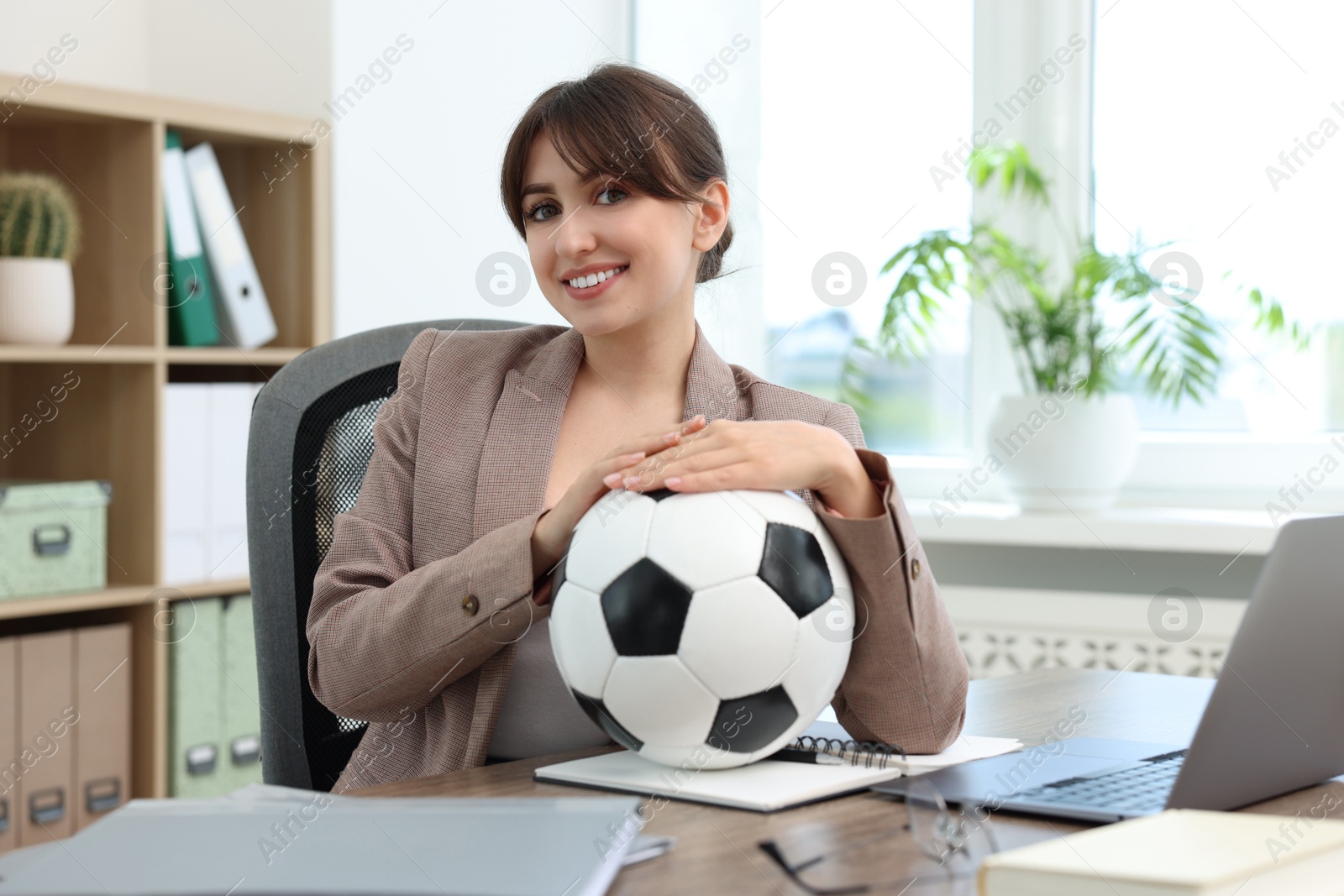 Photo of Smiling employee with soccer ball at table in office