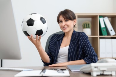 Photo of Smiling employee with soccer ball at table in office