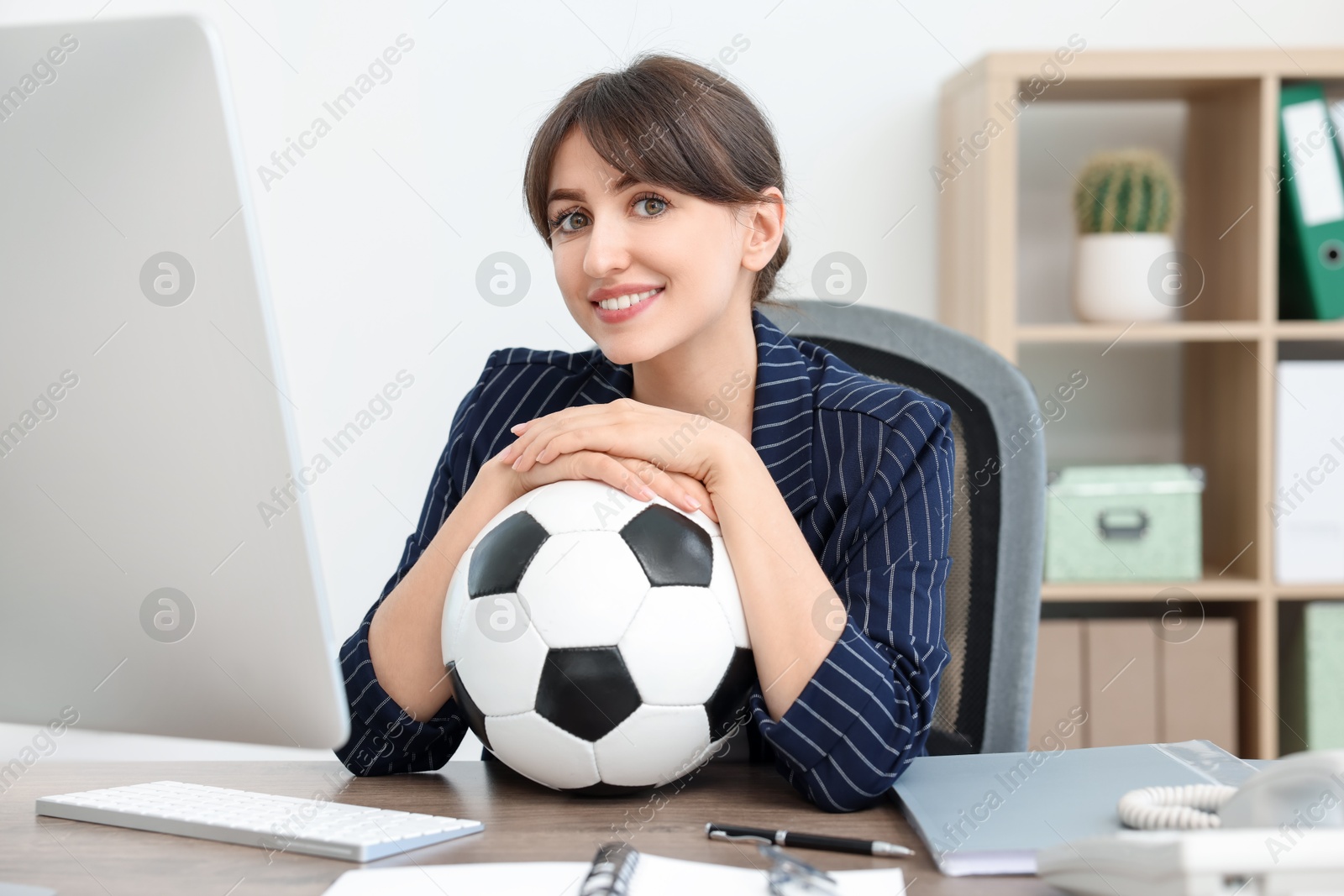 Photo of Smiling employee with soccer ball at table in office