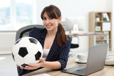 Photo of Smiling employee with soccer ball at table in office