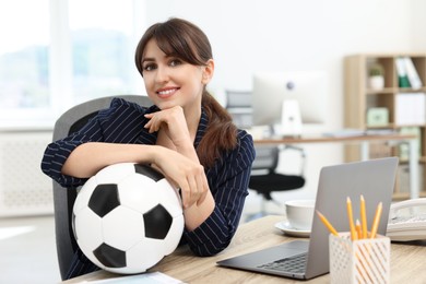 Smiling employee with soccer ball at table in office