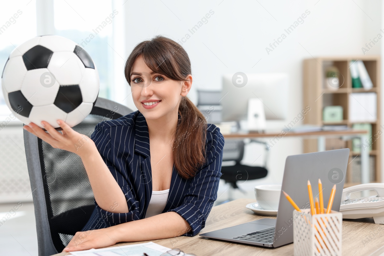 Photo of Smiling employee with soccer ball at table in office