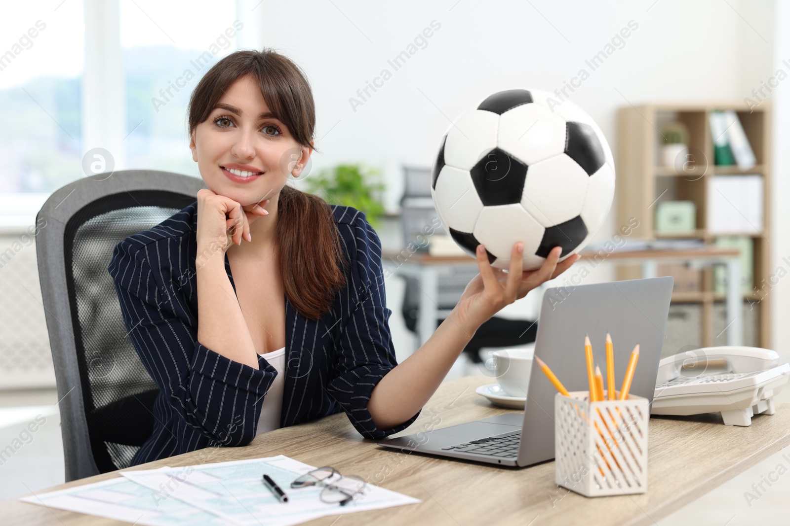 Photo of Smiling employee with soccer ball at table in office