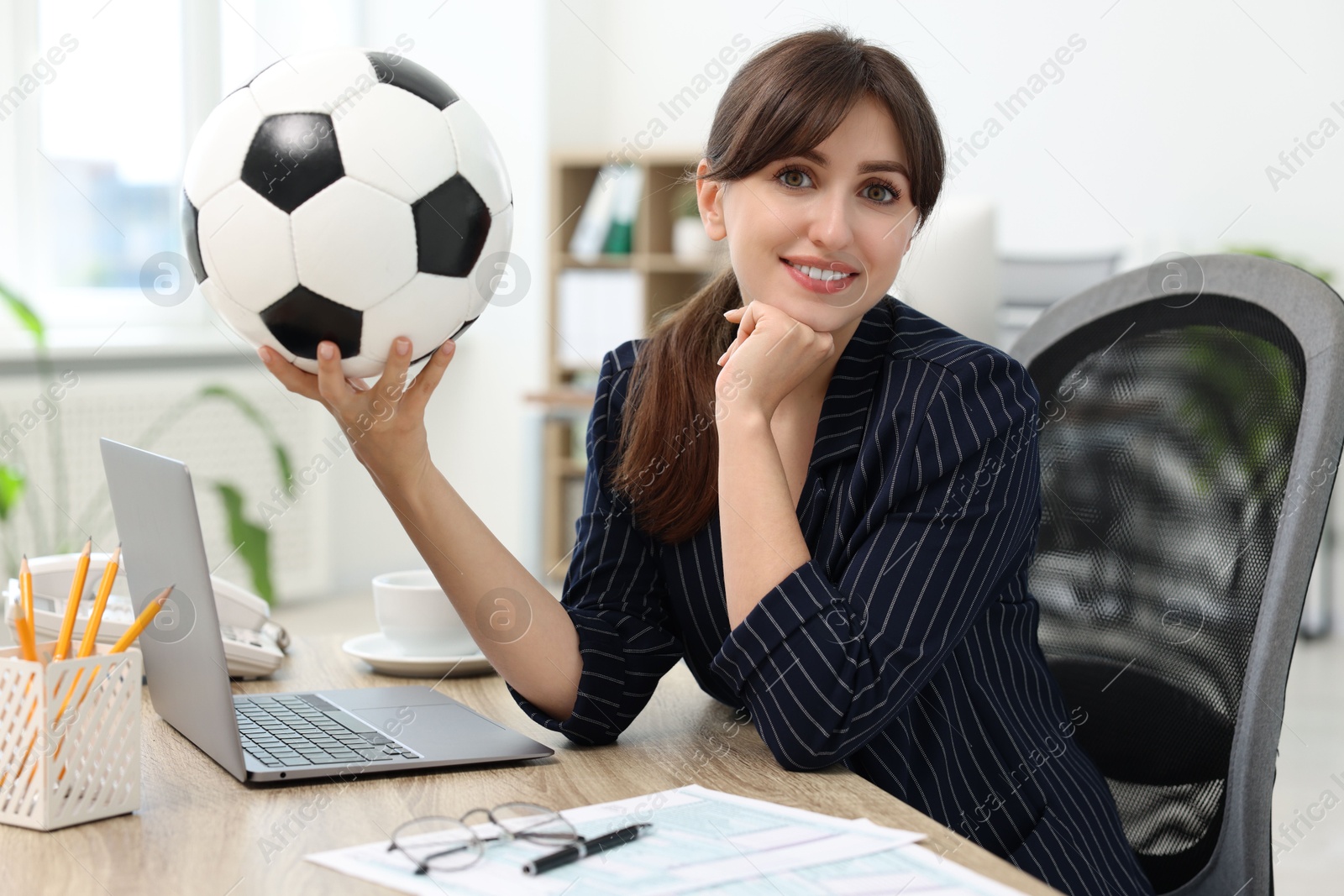 Photo of Smiling employee with soccer ball at table in office