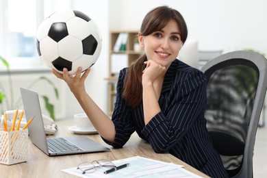 Photo of Smiling employee with soccer ball at table in office