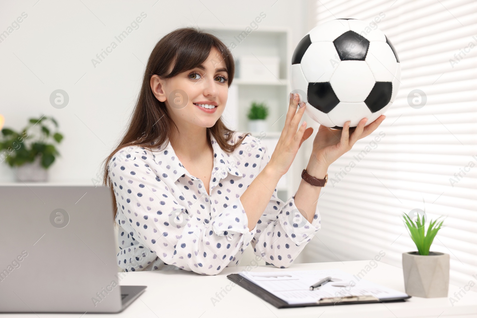 Photo of Smiling employee with soccer ball at table in office