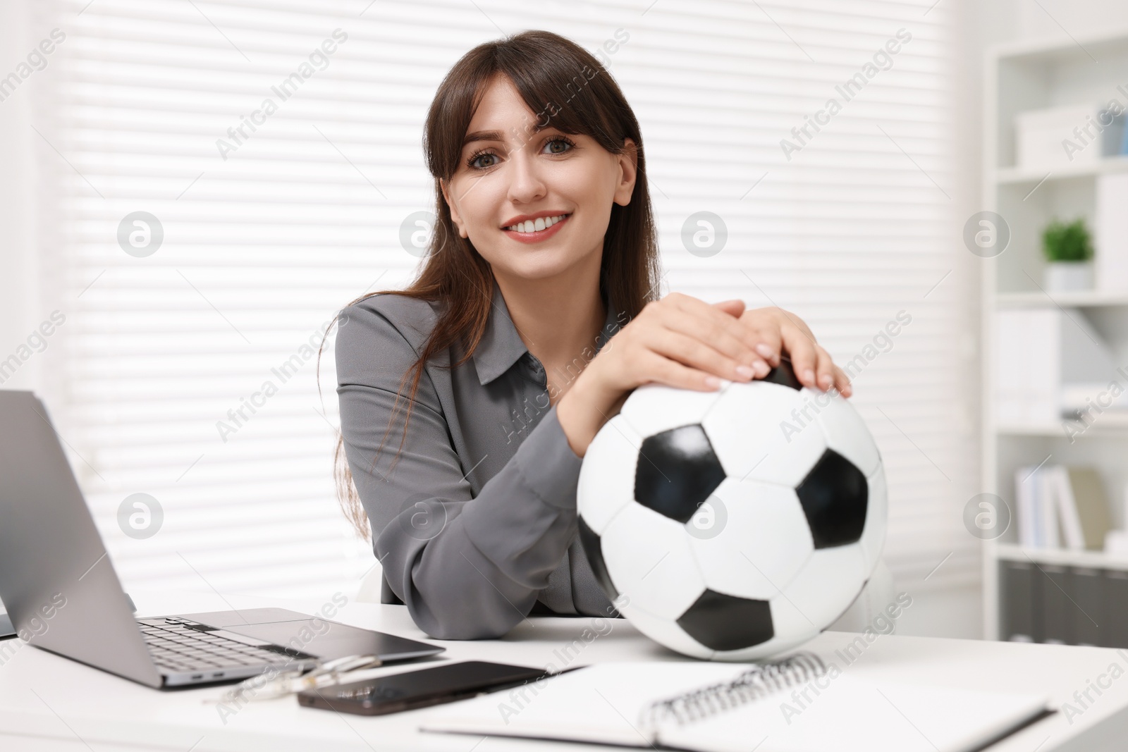 Photo of Smiling employee with soccer ball at table in office