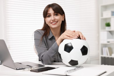 Smiling employee with soccer ball at table in office