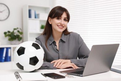 Smiling employee with soccer ball at table in office