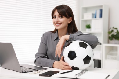 Photo of Smiling employee with soccer ball at table in office