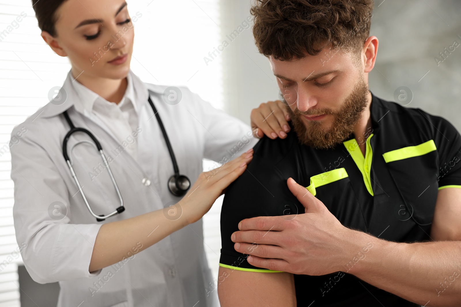 Photo of Sports injury. Doctor examining patient's shoulder in hospital