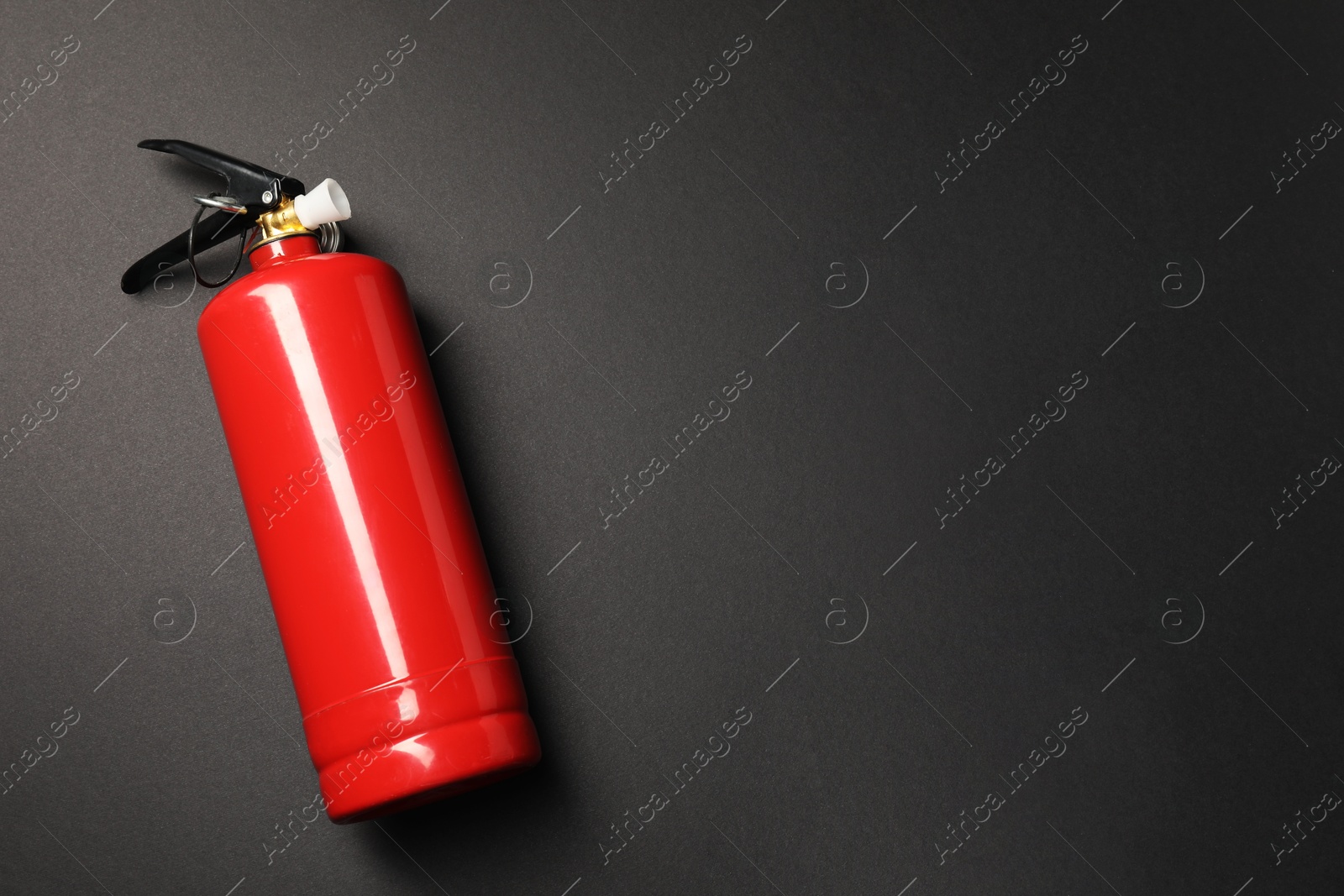 Photo of One red fire extinguisher on dark gray background, top view. Space for text