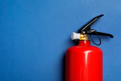 Photo of One red fire extinguisher on blue background, top view. Space for text