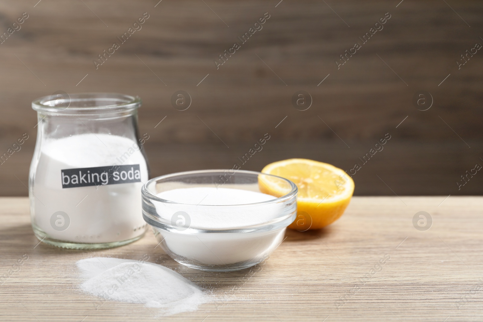 Photo of Baking soda and lemon on wooden table, space for text