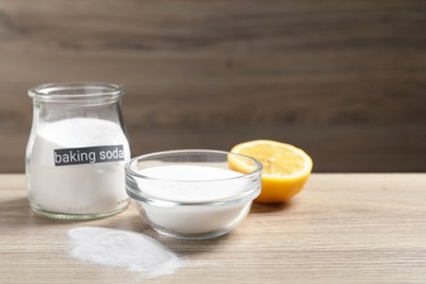 Photo of Baking soda and lemon on wooden table, space for text