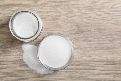 Photo of Baking soda in glass jar on wooden table, top view. Space for text