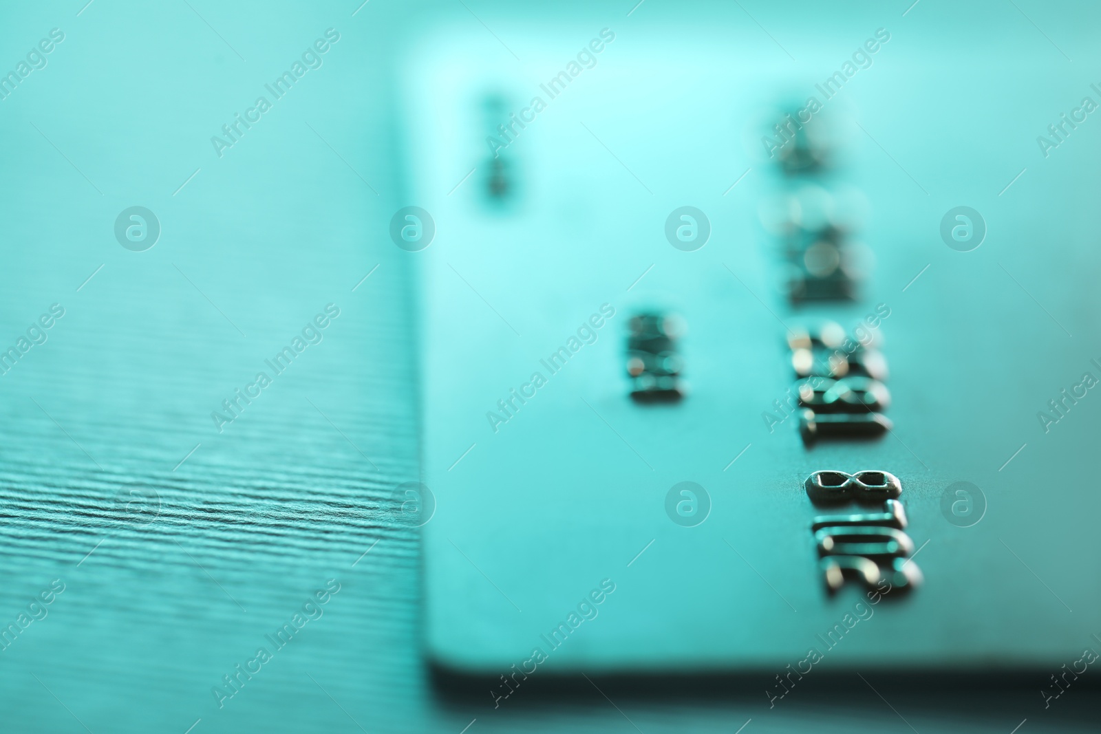 Photo of One credit card on turquoise background, closeup. Space for text