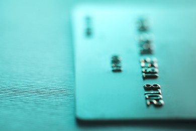 One credit card on turquoise background, closeup. Space for text