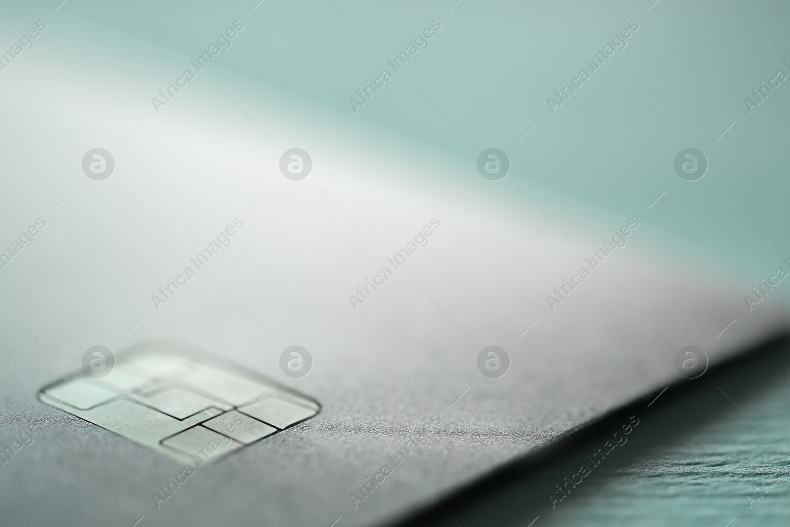 Photo of One credit card on turquoise background, macro view