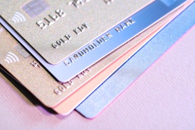 Many credit cards on pink background, closeup