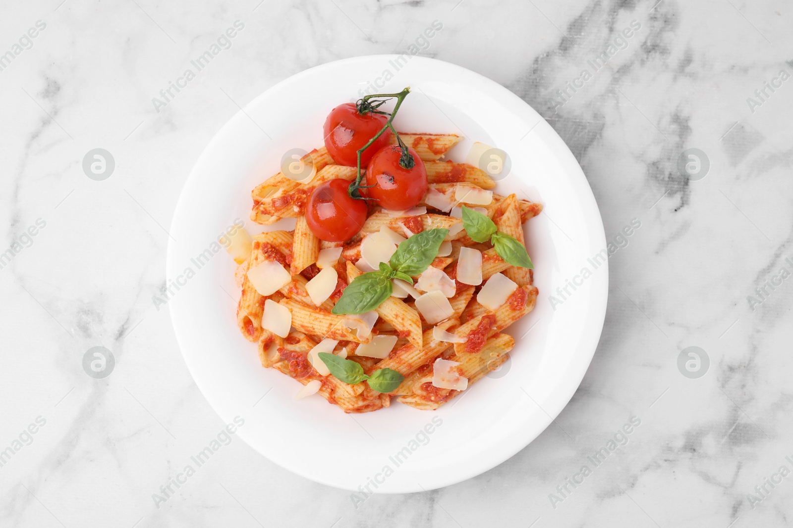 Photo of Tasty pasta with tomato sauce, cheese and basil on white marble table, top view