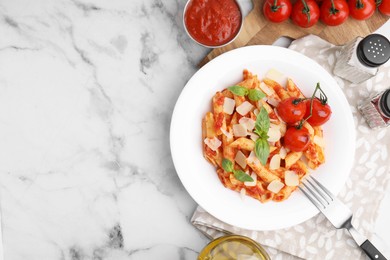 Photo of Tasty pasta with tomato sauce, cheese and basil served on white marble table, top view. Space for text