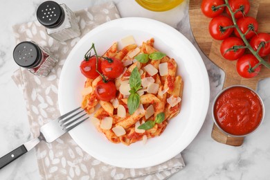 Tasty pasta with tomato sauce, cheese and basil served on white marble table, top view