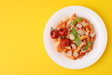 Photo of Tasty pasta with tomato sauce, cheese and basil on yellow background, top view. Space for text