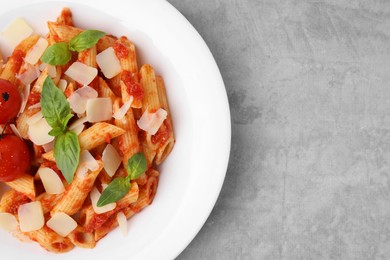 Photo of Tasty pasta with tomato sauce, cheese and basil on grey table, top view. Space for text