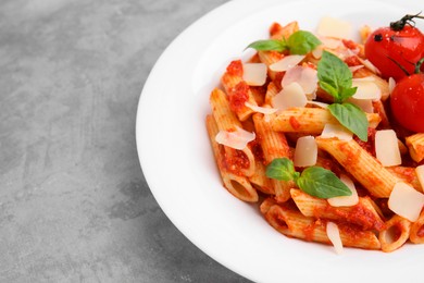 Photo of Tasty pasta with tomato sauce, cheese and basil on grey table, space for text